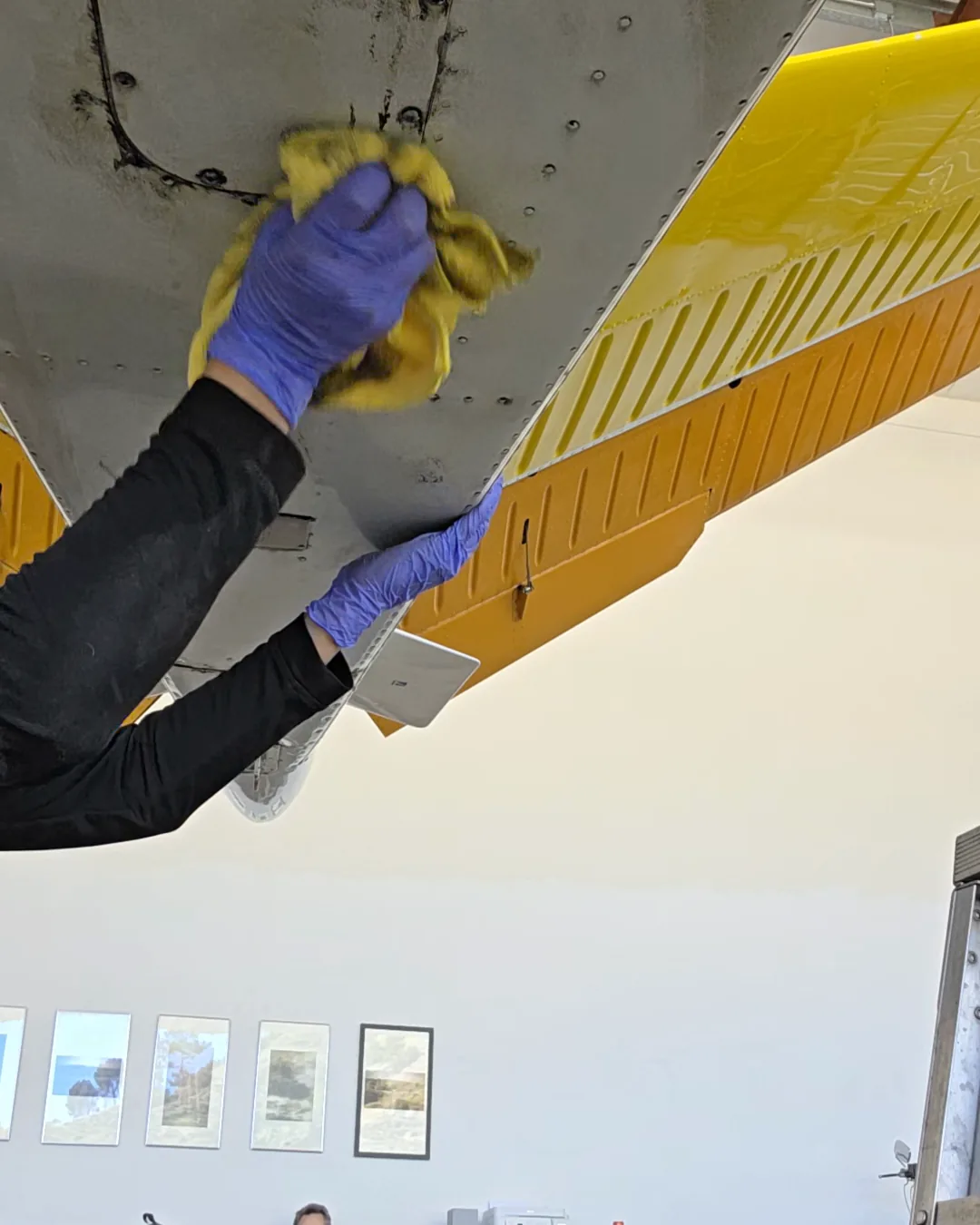 Joel polishing the bare aluminum belly of an aircraft by hand in a California hangar
