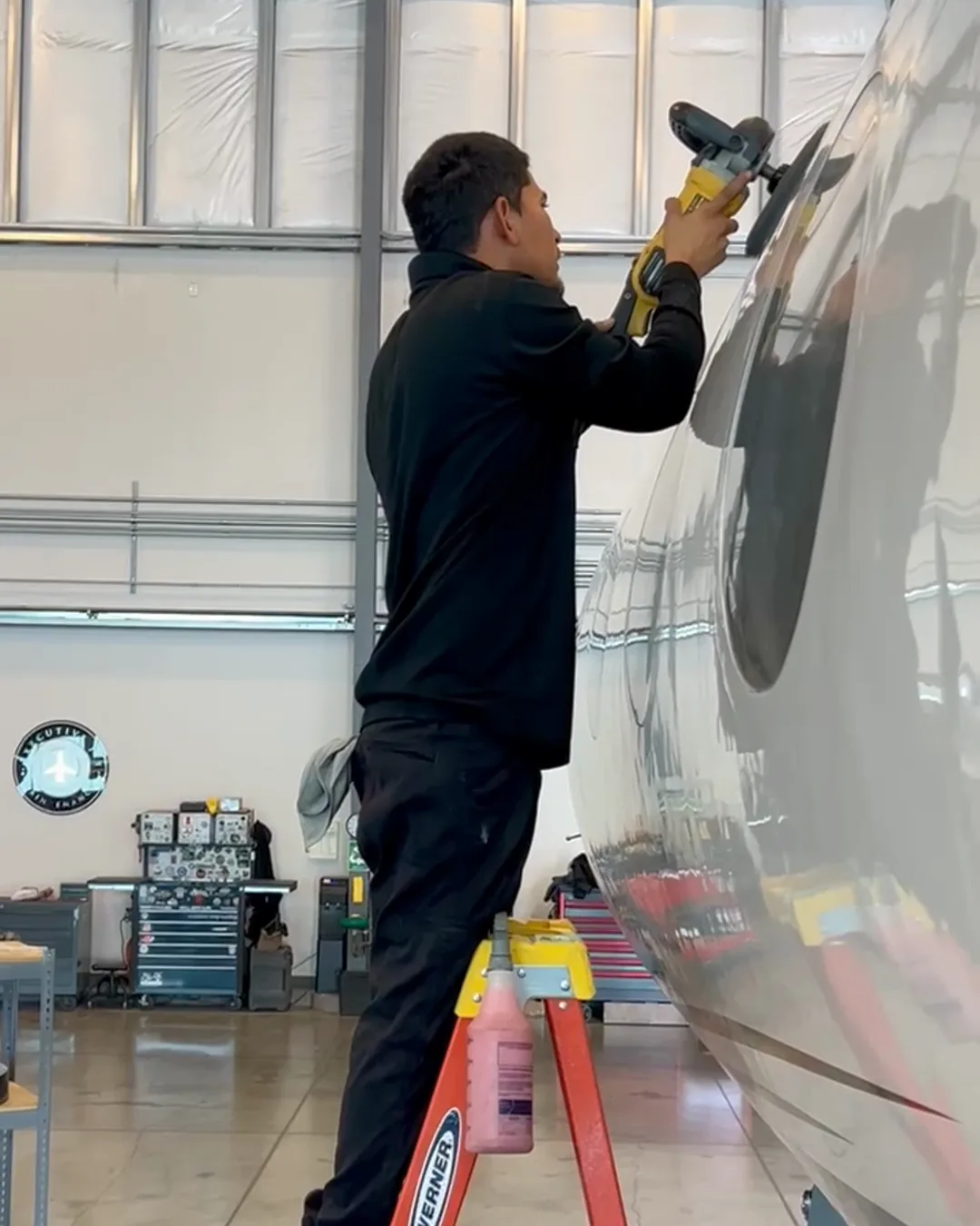 Joel Espiritu polishing the mirror finish aluminum fuselage of an aircraft inside a California hangar