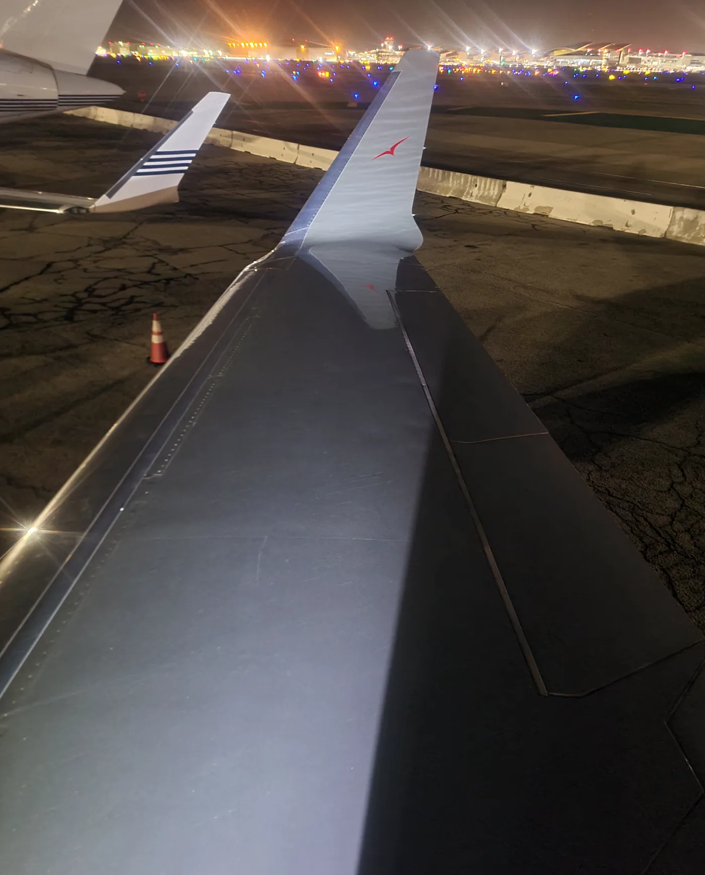 Aircraft wing at night on a lit airport ramp in California